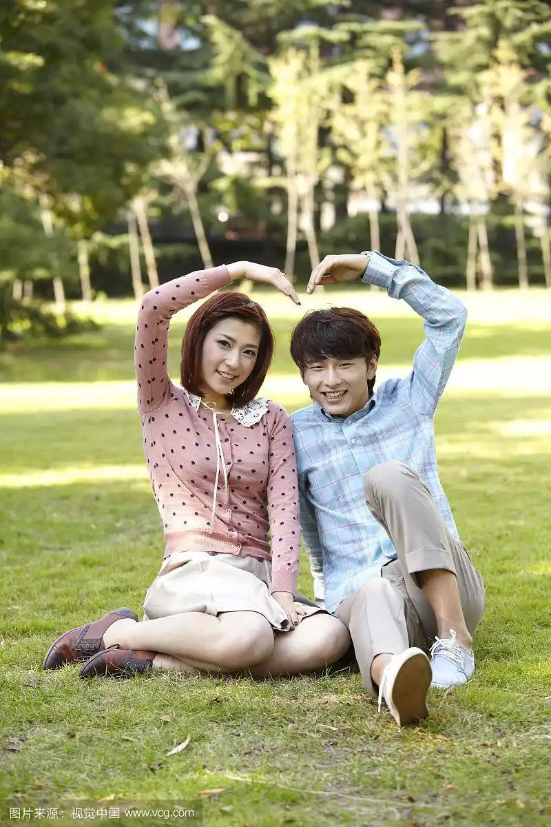 情侣在公园里一起做心形手势的照片