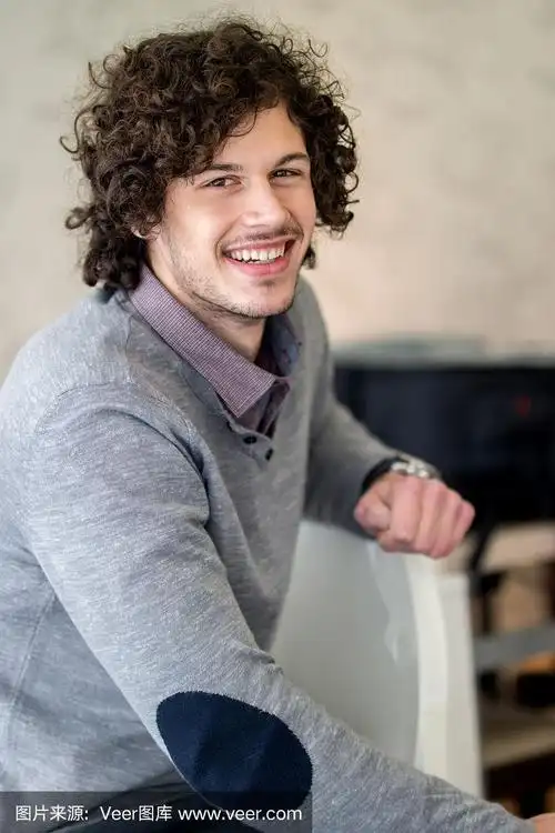 一个卷头发的男人在室内看着镜头.