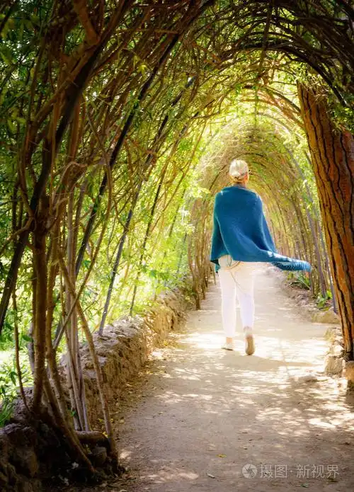西班牙巴塞罗那公园里的一个女人在林荫小道上散步