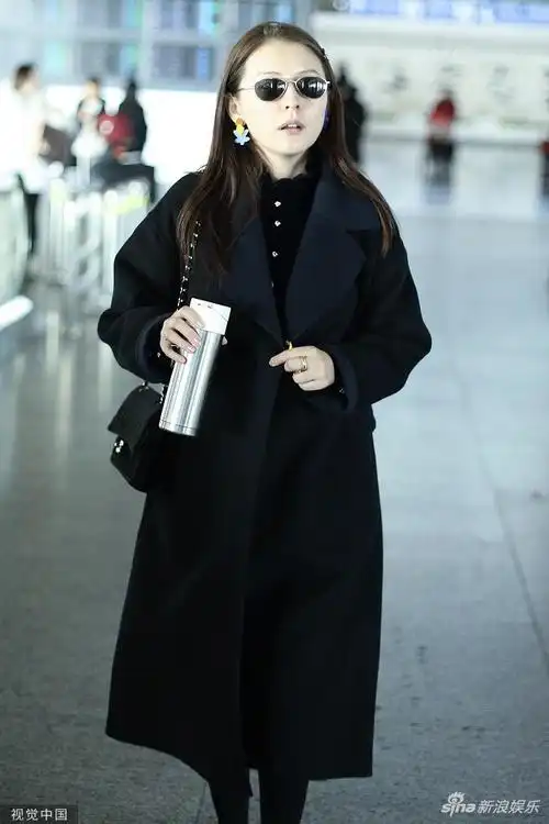 热依扎戴彩色耳环俏皮可爱 手拿保温杯面露笑容