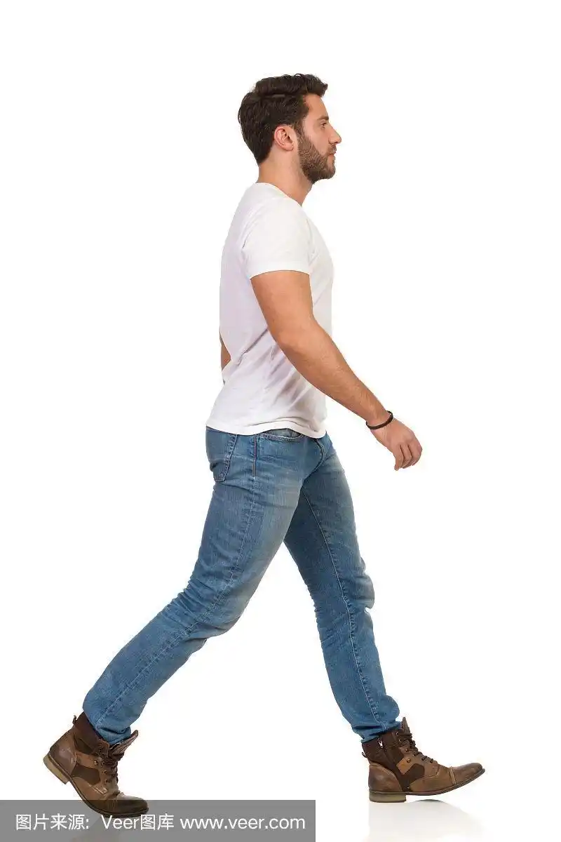 穿着牛仔裤和白色t恤的年轻人正在走路.侧视图
