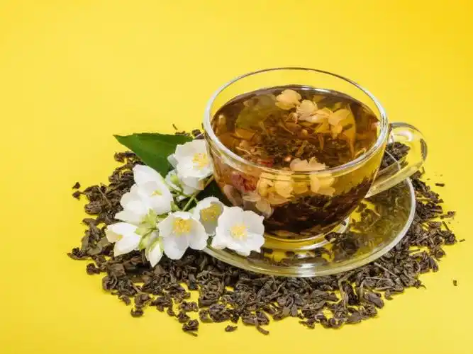 a cup of jasmine tea with jasmine flowers on a yellow background