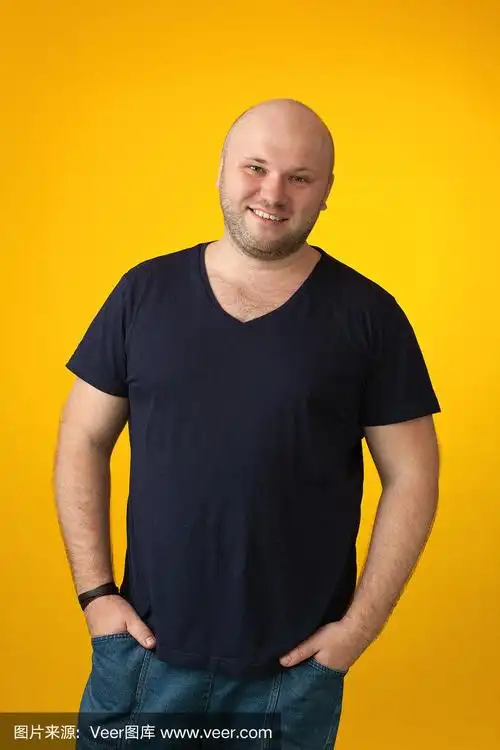 一名35岁剃着光头的大胡子男子的工作室肖像,他穿着一件蓝色t恤,背景