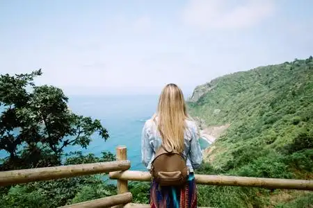 一位年轻的女游客从山上望向大海的背影照片