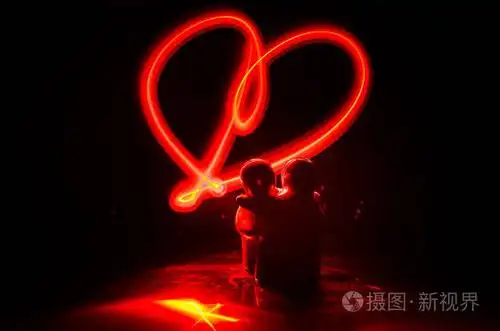 两个年轻的恋人画一颗心在火上夫妇和爱语在深色背景上的剪影