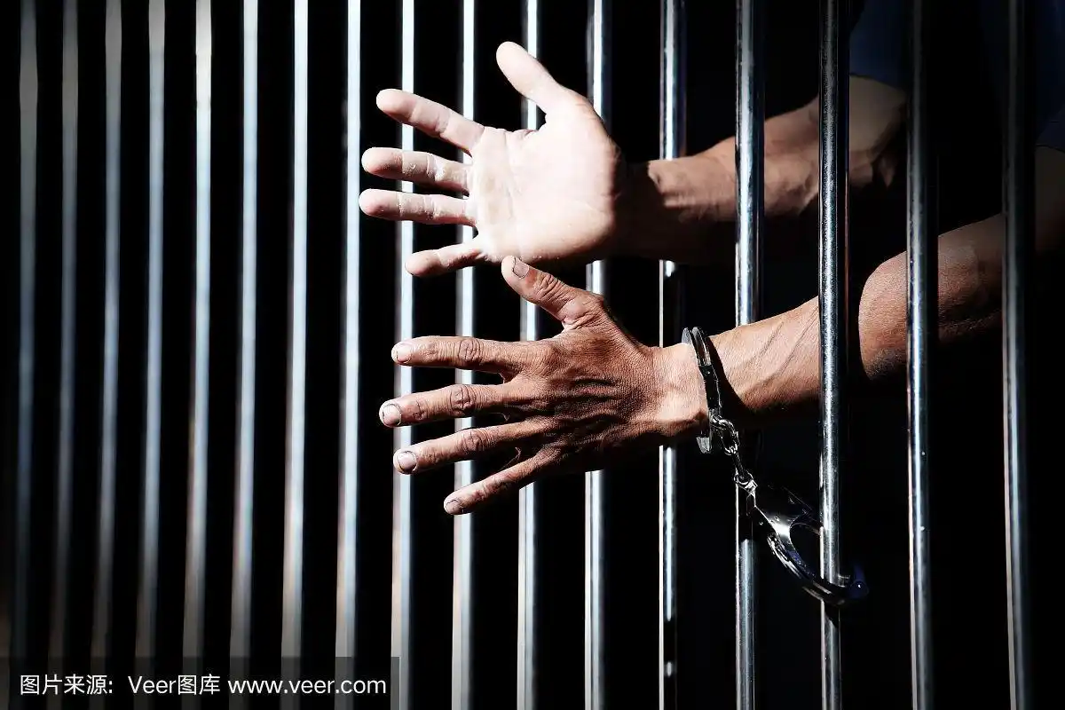 监狱背景中囚犯手带手铐的特写