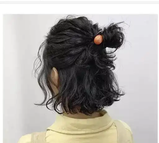 可以参考一下这一位女生的披肩发丸子头发型的扎发,她把头顶上面的