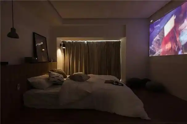 床尾的大白墙,投影仪的画面直接投射在上面,让卧室在夜晚就成为姻个