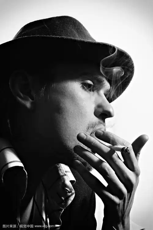 一个戴着帽子的年轻吸烟男子的黑白肖像