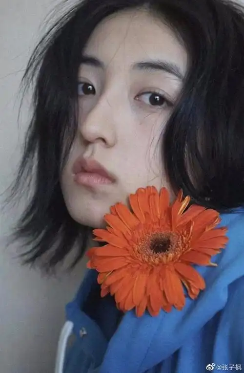 张子枫晒九宫格自拍穿蓝色卫衣持花摆pose
