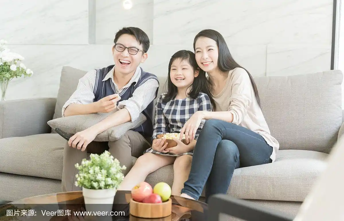 幸福的亚洲家庭一起在客厅的沙发上看电视.家庭和家庭的概念.