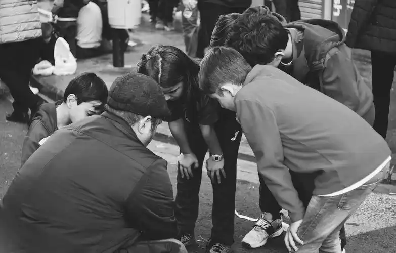 一群小孩围着一个大人不知在看什么.