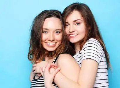 两个漂亮的十几岁的女朋友微笑着拥抱,玩得很开心照片