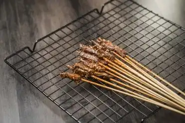 黑色烤架上放着几串撒着辣椒面的油炸牛肉小串