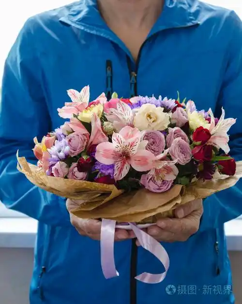 男人手中捧着不同花朵的玫瑰和菊花五颜六色的花束不同的鲜花特写