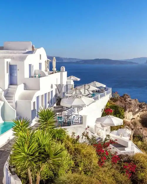 希腊圣托里尼村的白色建筑外观,带有游泳池和花园,背景是爱琴海.
