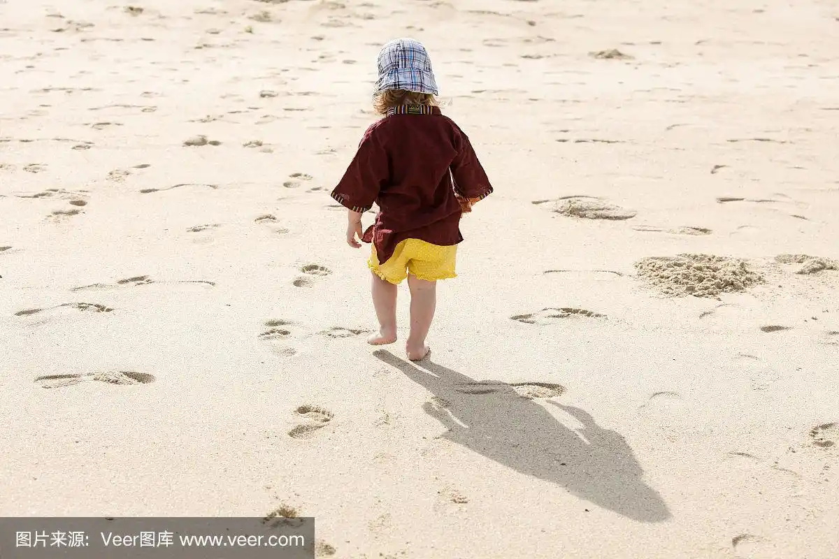 孩子在沙滩上留下小脚印,光着脚玩耍