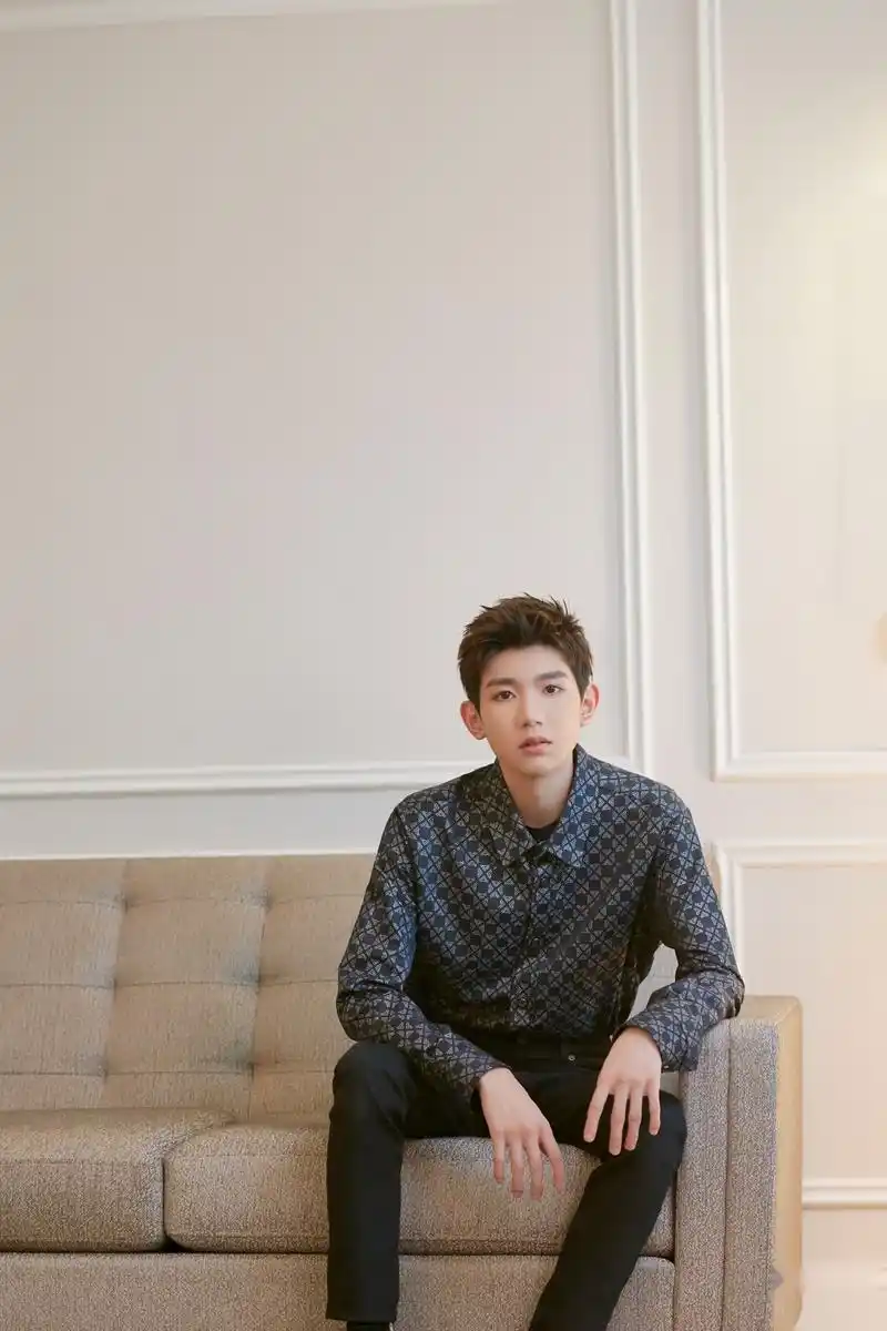 照片中王源随性坐在沙发一角直视镜头,眼神杀霸气十足