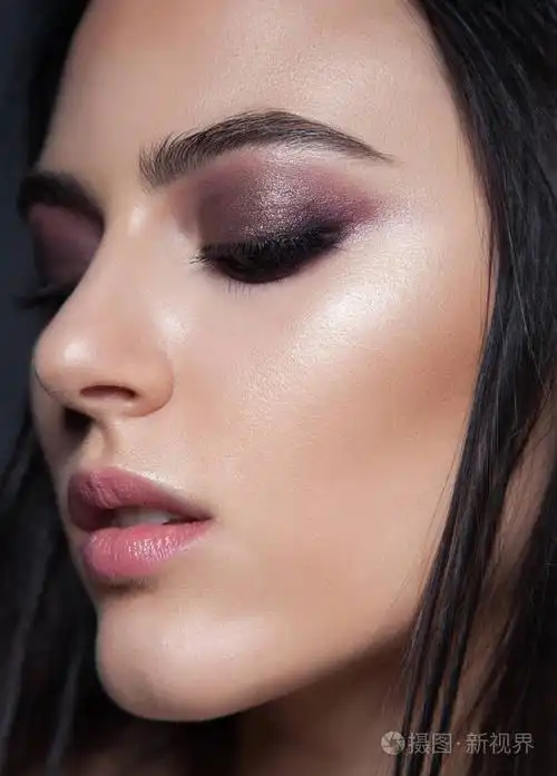 特写美女肖像.深色的紫色化妆.黑色背景的魅力女人.发光的皮肤