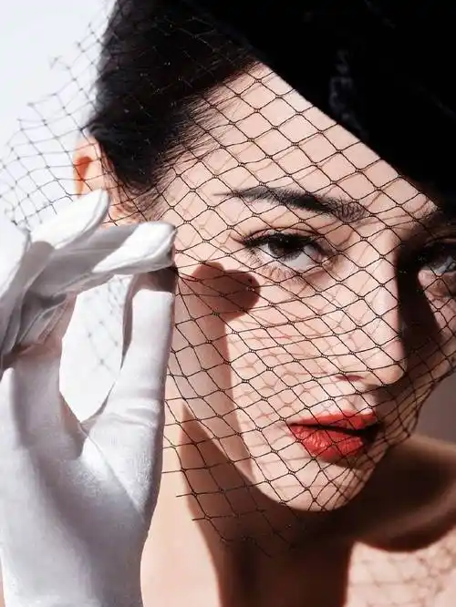 图中,迪丽热巴身着黑色丝绒礼裙,搭配同色系黑纱礼帽和白手套,五官