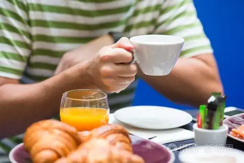 男人吃早餐有羊角面包, 咖啡和新鲜的橙汁