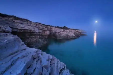 岩石海岸和满月在夏天的夜晚.海洋湖泊