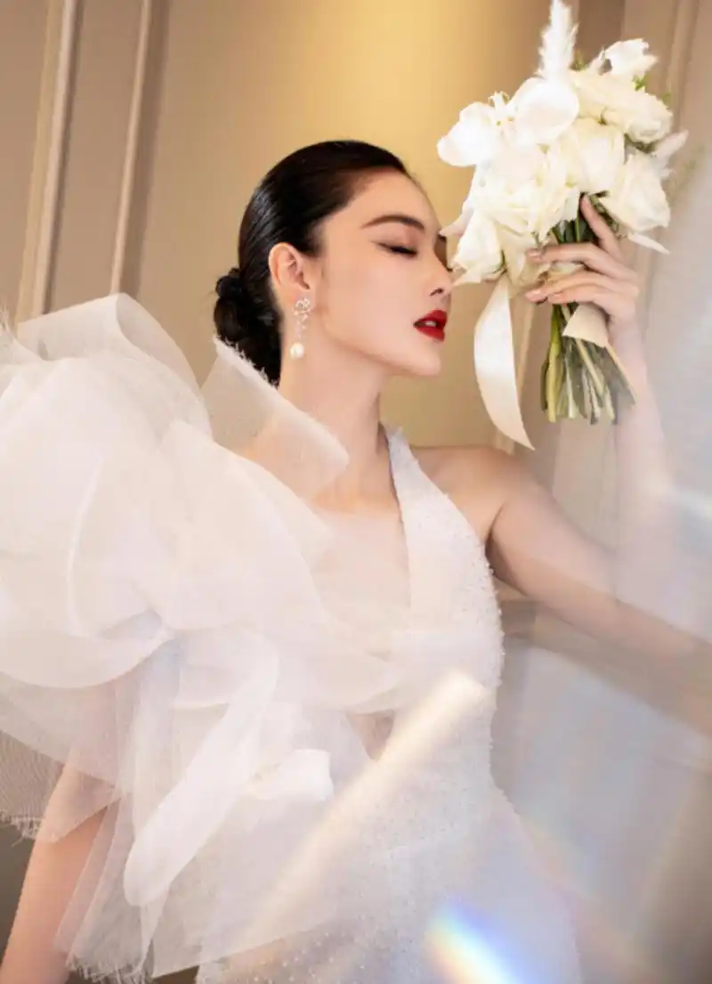 张馨予将头发束起,白色婚纱,显得妩媚迷人.珍珠耳饰点缀,恰到好处.