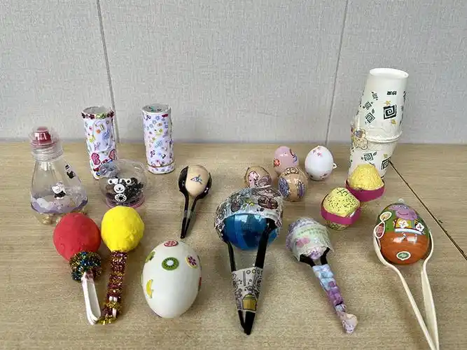 把大豆装进矿泉水瓶,制作一个简单的沙锤;将扭扭棒系上几个铃铛,制作