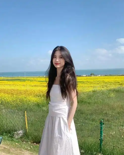 阳光下的微笑:美丽女子油菜花田边摄影