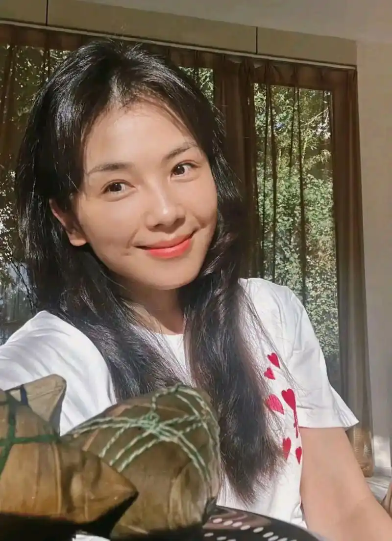 照片中,刘涛穿着一件印有红色桃心的白色t恤,过肩长发随意披着,笑容