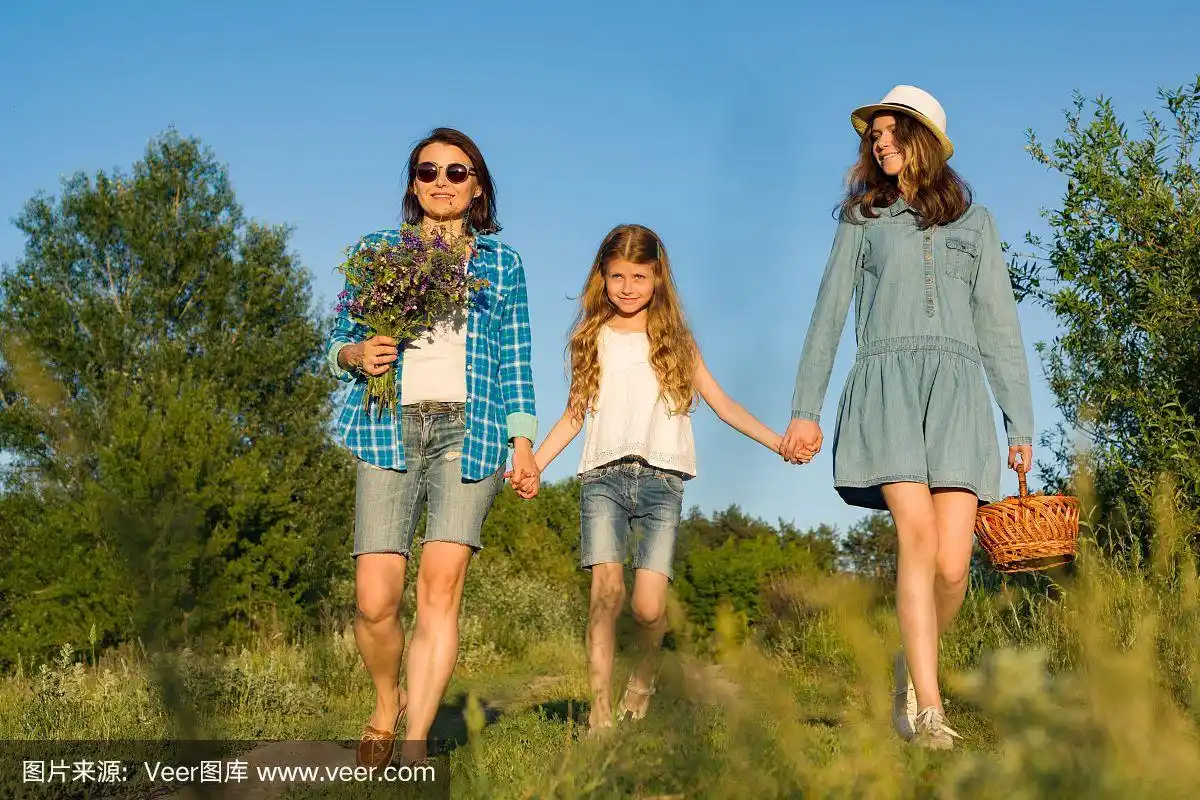 母亲和女儿手牵着手,走在乡间小路上.