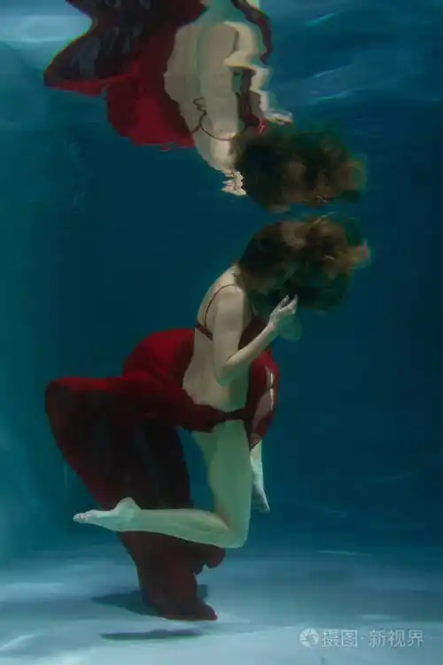 美丽的白种人长发女人独自穿着红色性感内衣在水下游泳