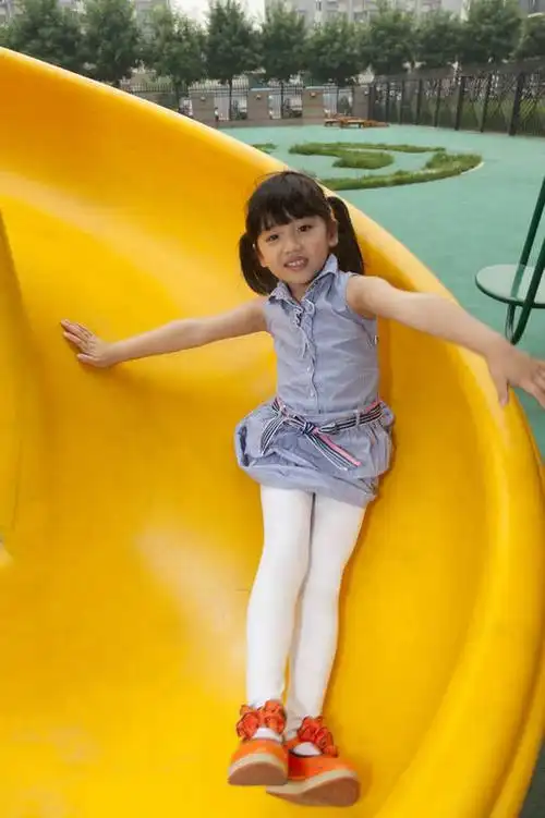 小女孩在幼儿园内玩滑梯