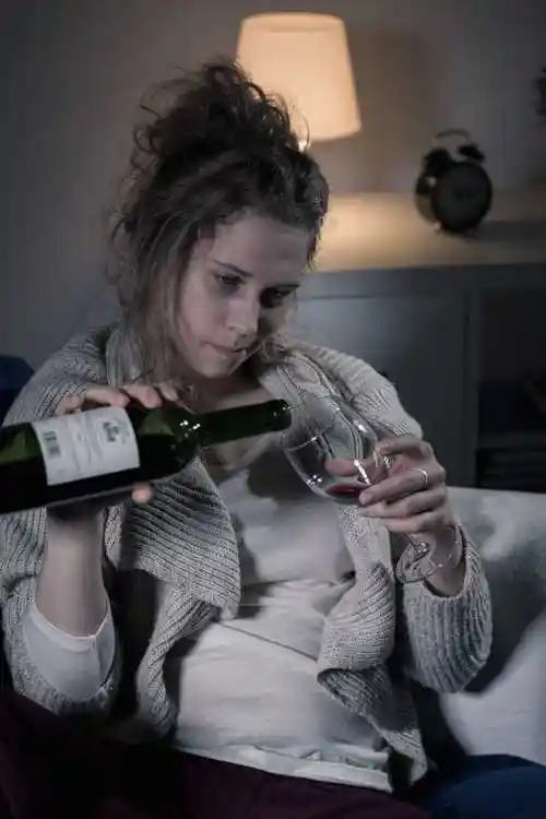 喝酒的年轻女人图片-坐在桌子旁边倒酒的女人素材-高清图片-摄影照片