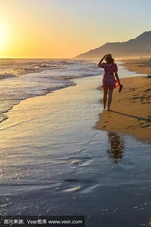 日落时分,一个女人在海滩上散步.