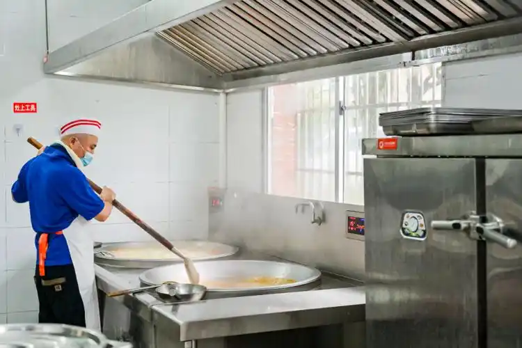 公益厨房内,工作人员在为学生准备餐食.