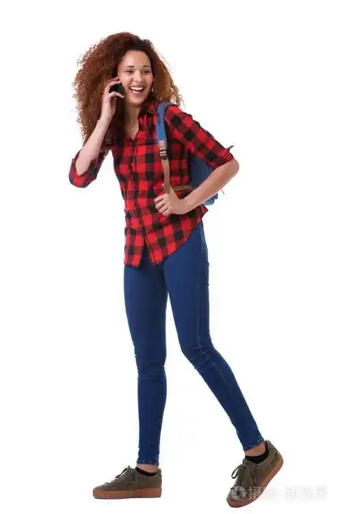 年轻女子的全身肖像走在孤立的白色背景与手机和袋子