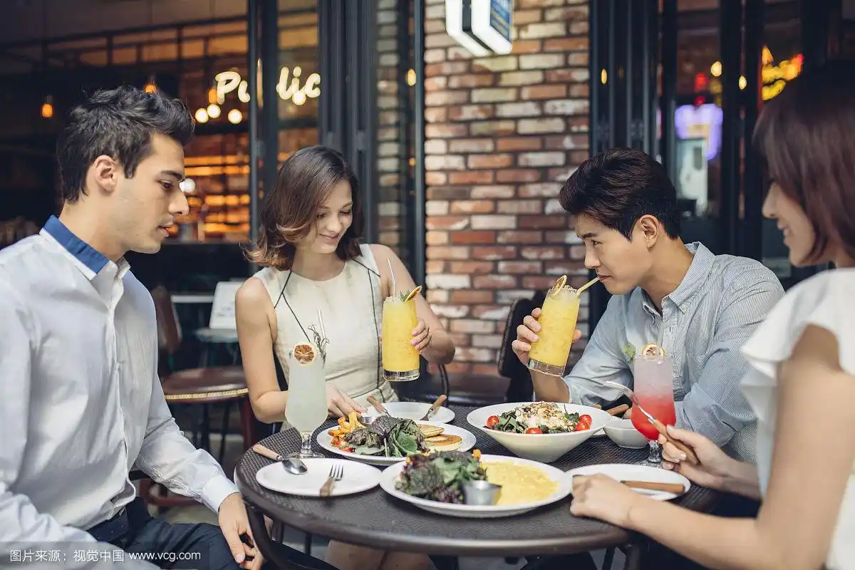 两个年轻男人和两个女人在餐厅吃饭的照片