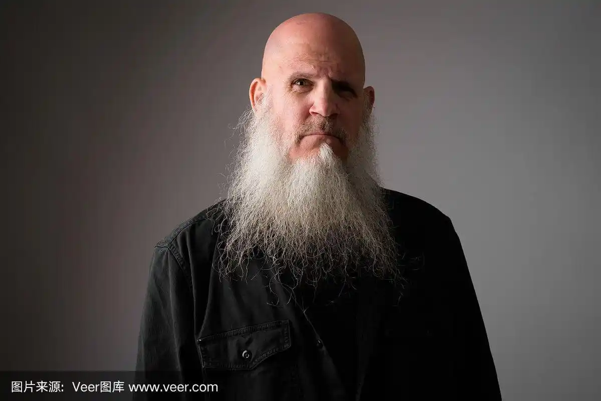 一张成熟的光头男人的脸,留着长长的灰胡子,看着镜头