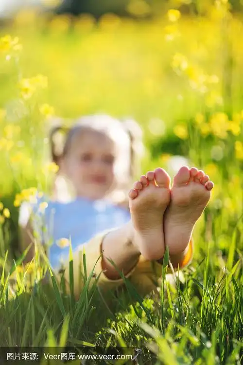 小女孩的脚在黄色的田野花