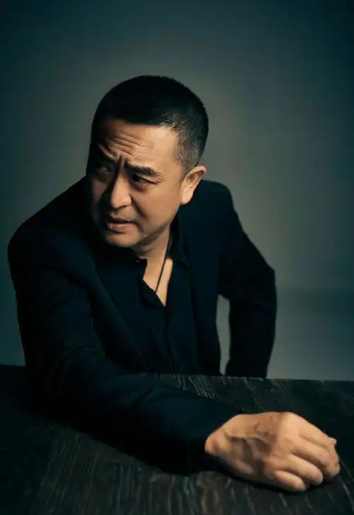 50岁张嘉益罕晒照,寸头黑西装再现霸总气质,被赞皱纹也性感