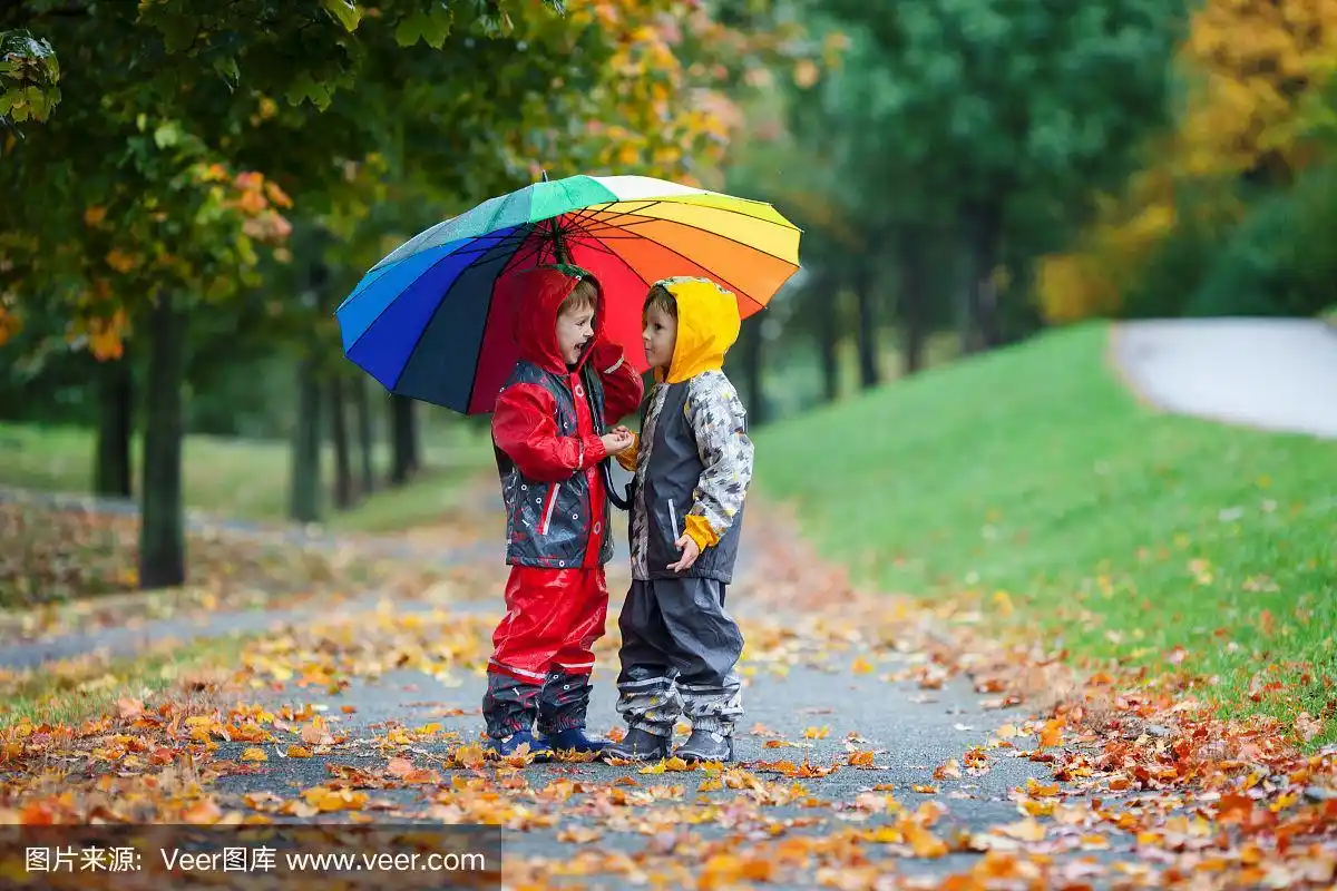两个可爱的孩子,男孩兄弟,在公园里打着伞