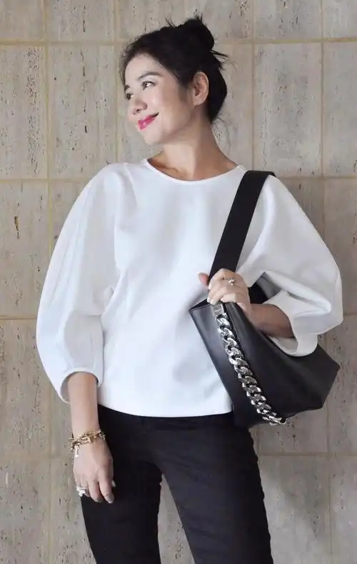 钟楚红穿了一件白色长袖宽松灯泡袖上衣搭配黑色高腰紧身裤,盘着丸子