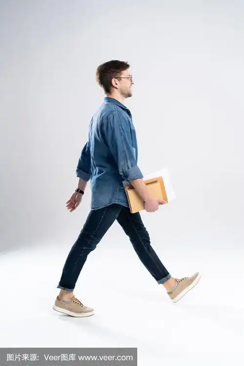 侧面的一个微笑的年轻人随意的人走,学生与书和笔记在白色的背景.