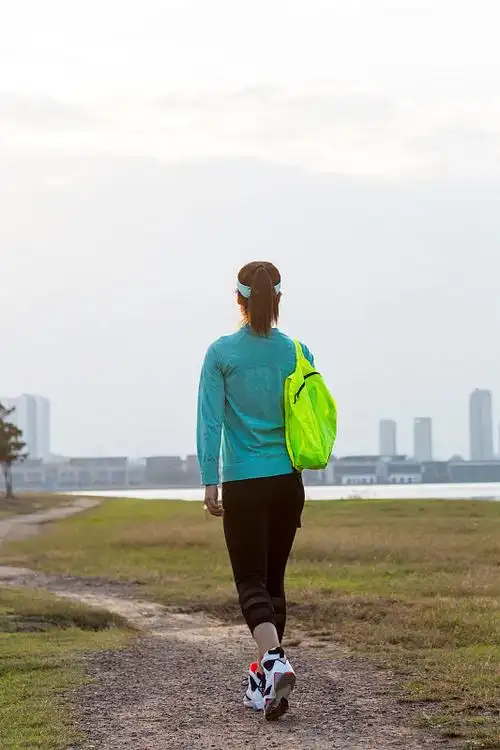 一个年轻女子背着背包在湖边散步的肖像图片下载