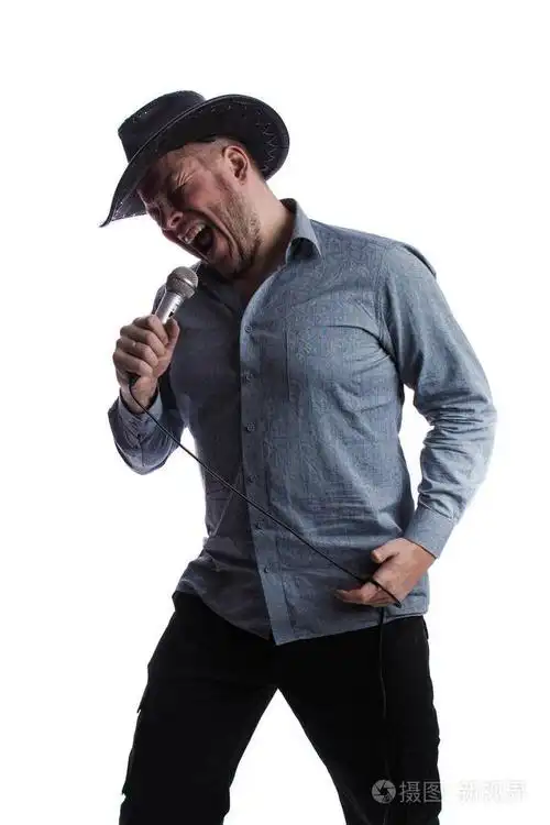 戴着黑色帽子,手里拿着麦克风,在演播室的白色背景上唱歌