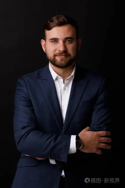 一个年轻英俊的商人在一个黑色的背景优雅的西装特写.成功职业的概念