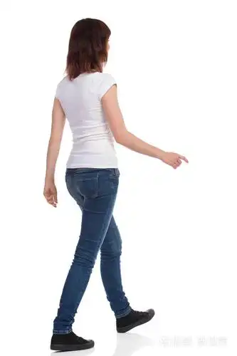 穿着白色 t恤,牛仔裤和运动鞋的年轻女士正在散步, 看着远处.