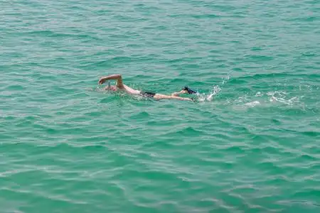 人在水肺面具游泳在蓝色海水照片