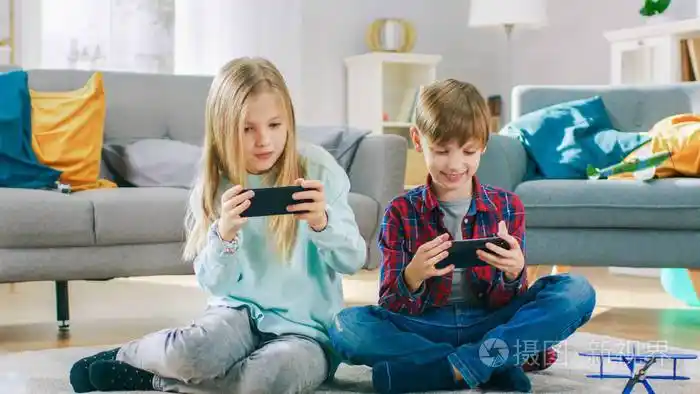 在家:可爱的小女孩和可爱的男孩在两部智能手机上玩电子竞技游戏.